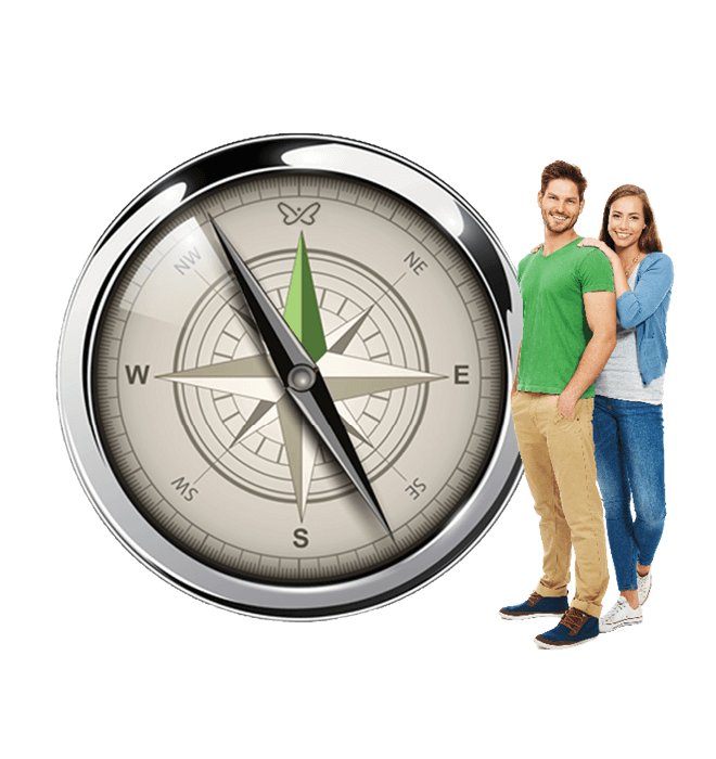 A young couple standing beside a large compass