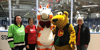 Mascots and skaters posing in front of a stadium skating rink