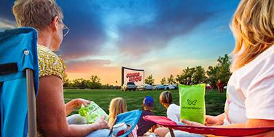 Two women watching a drive in movie with their children