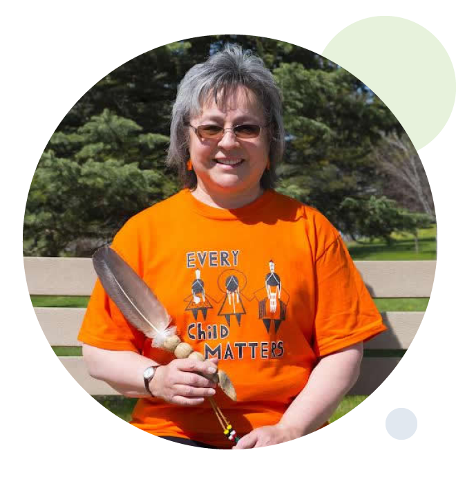 Phyllis Webstad wearing an orange shirt, holding a feather.