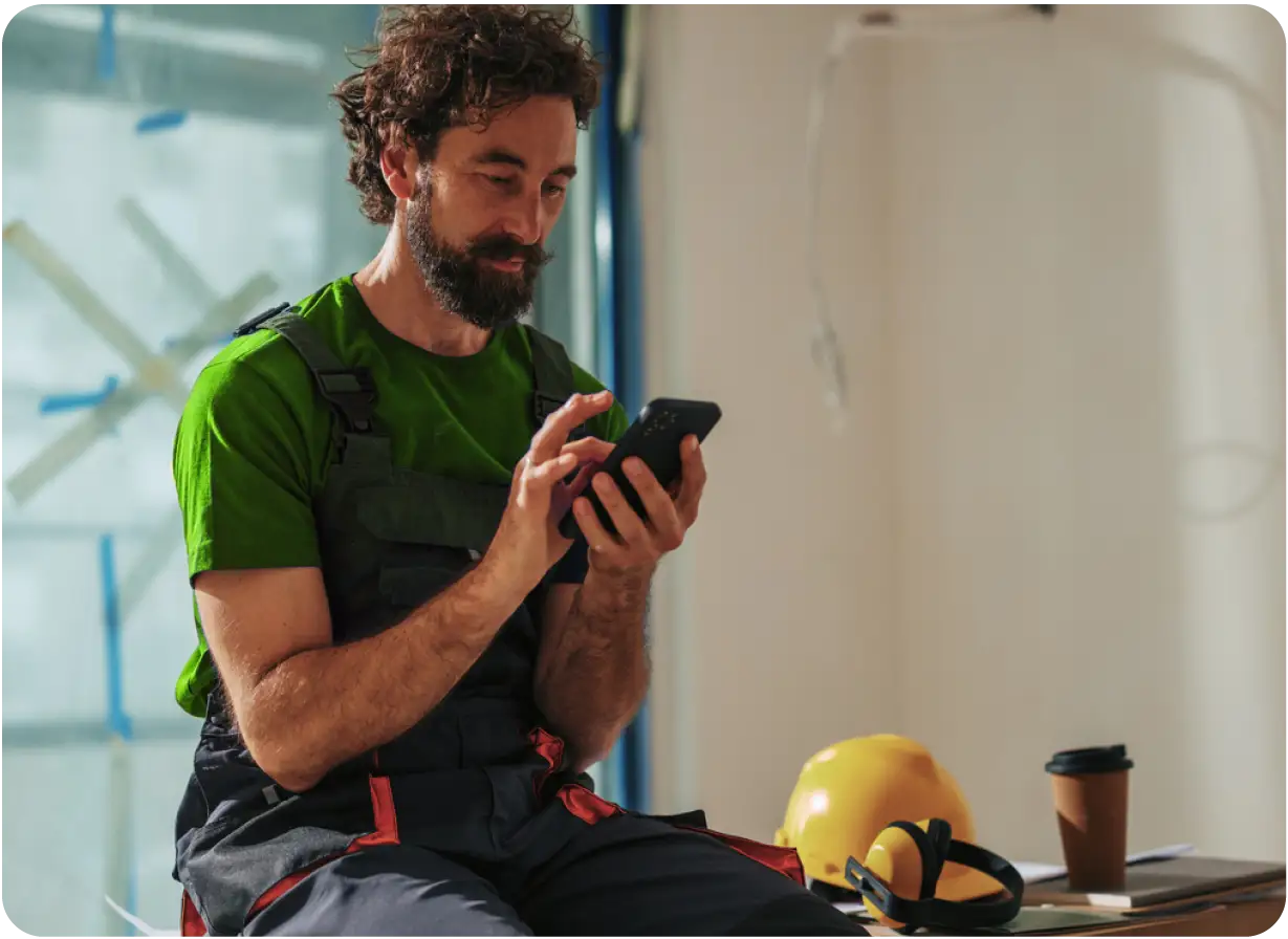 Man Using Phone on Coffee Break at Construction Job