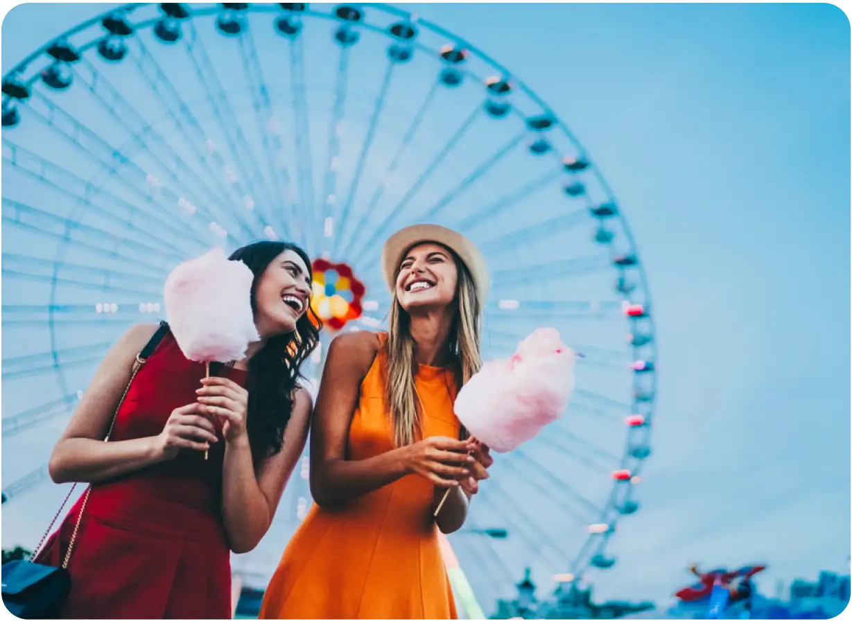 Two Friends Eating Cotton Candy at Amusement Park
