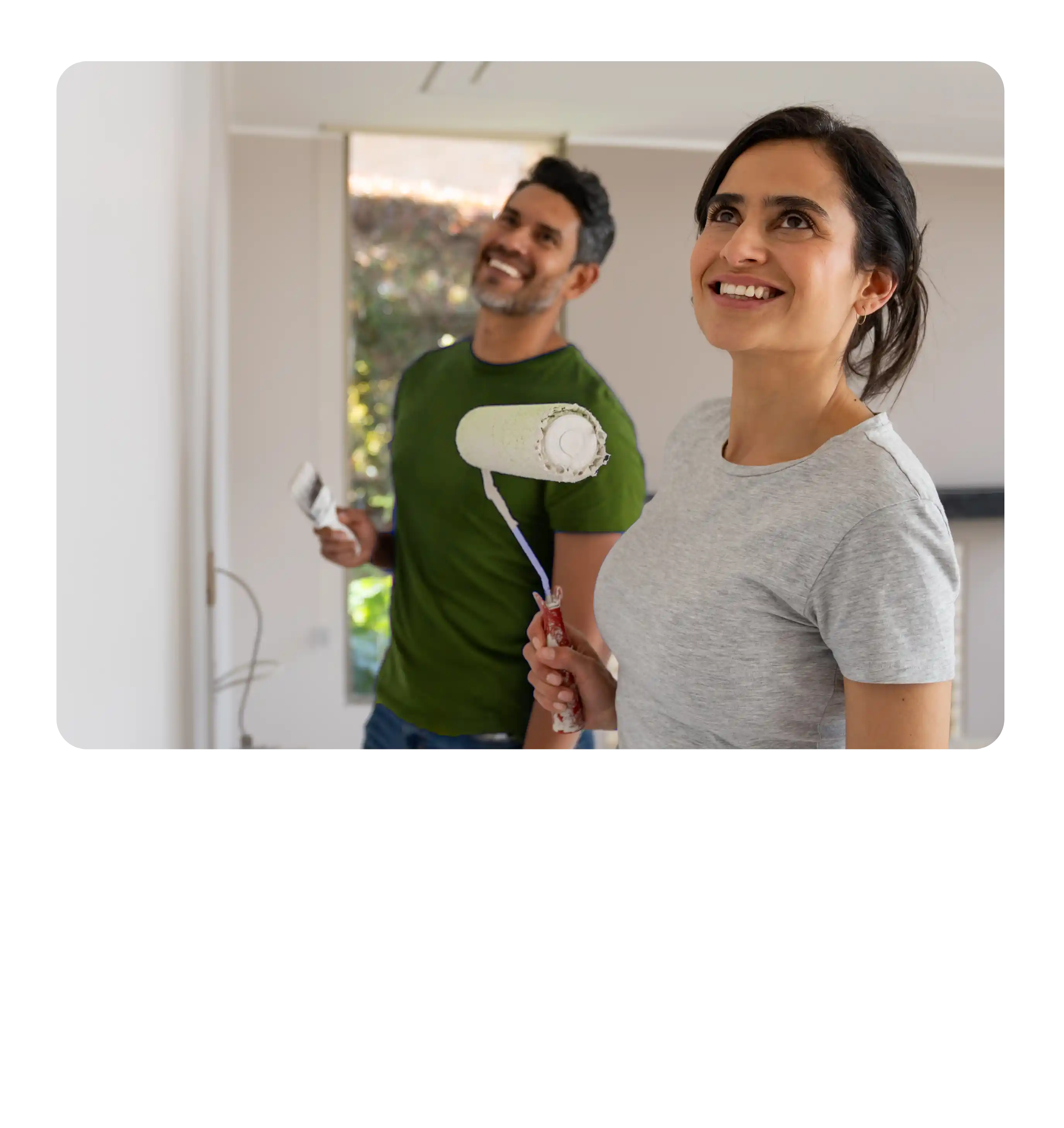 A smiling couple painting the walls of their home together.