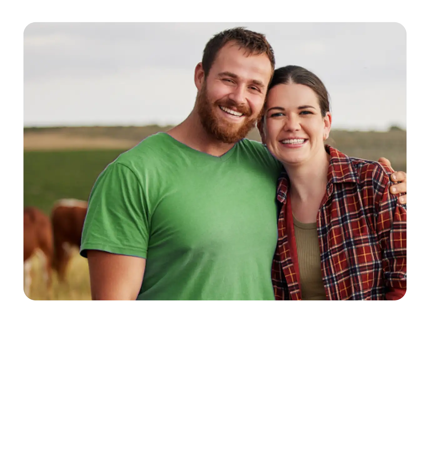 A smiling couple standing together outdoors on a farm.