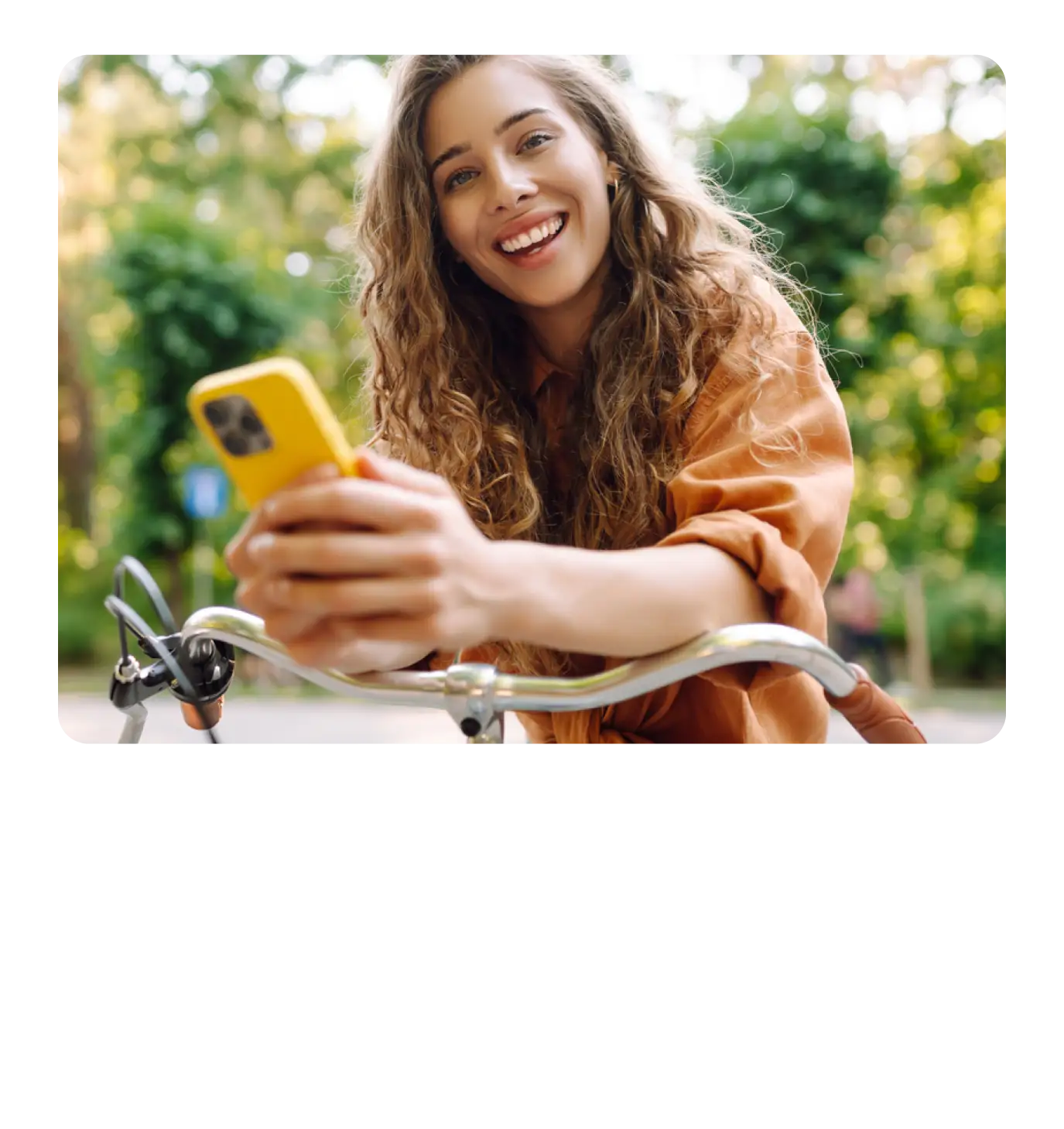 Smiling woman sitting on a bicycle with her phone