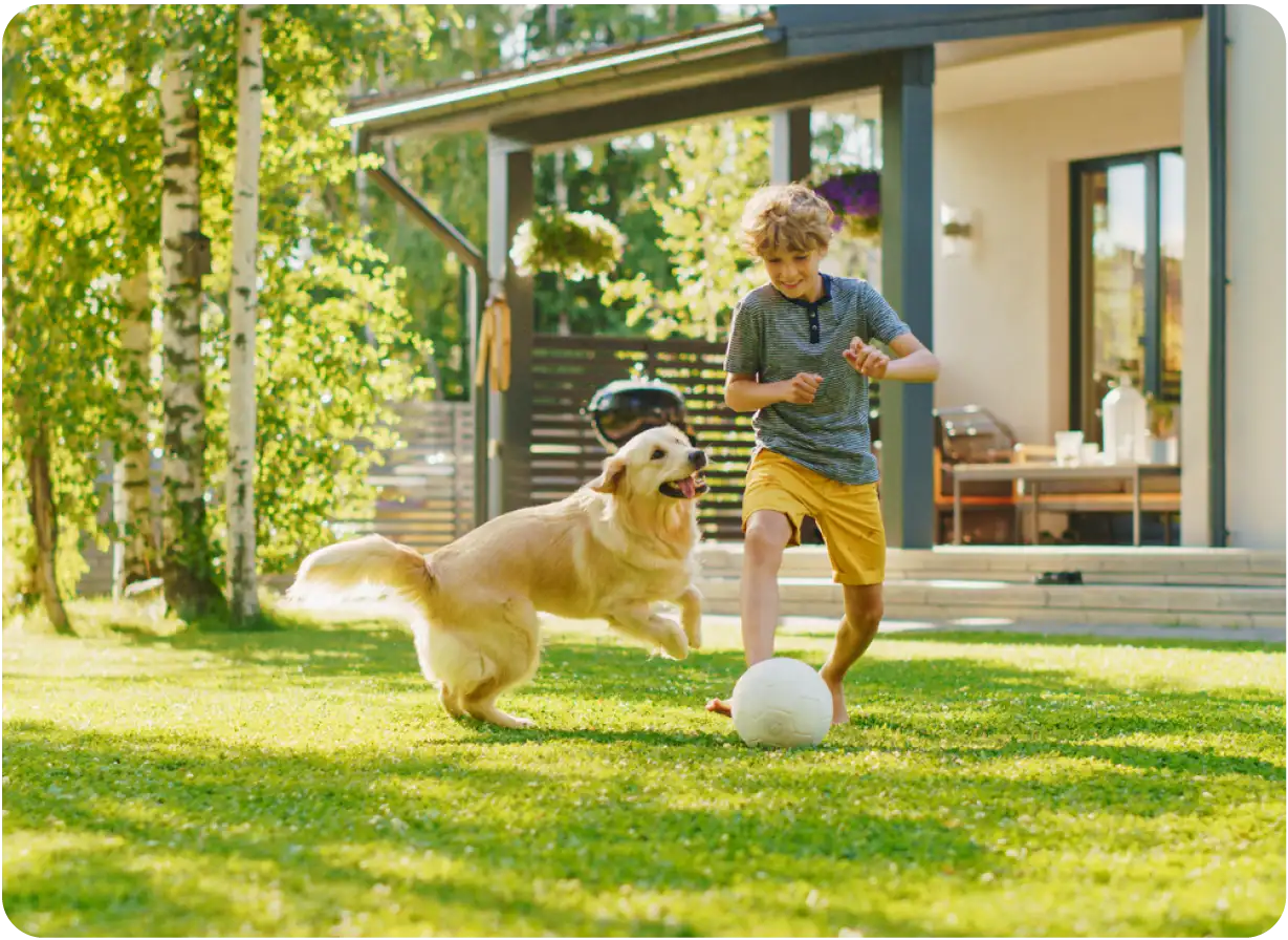 Boy Playing Soccer with Dog in Yard