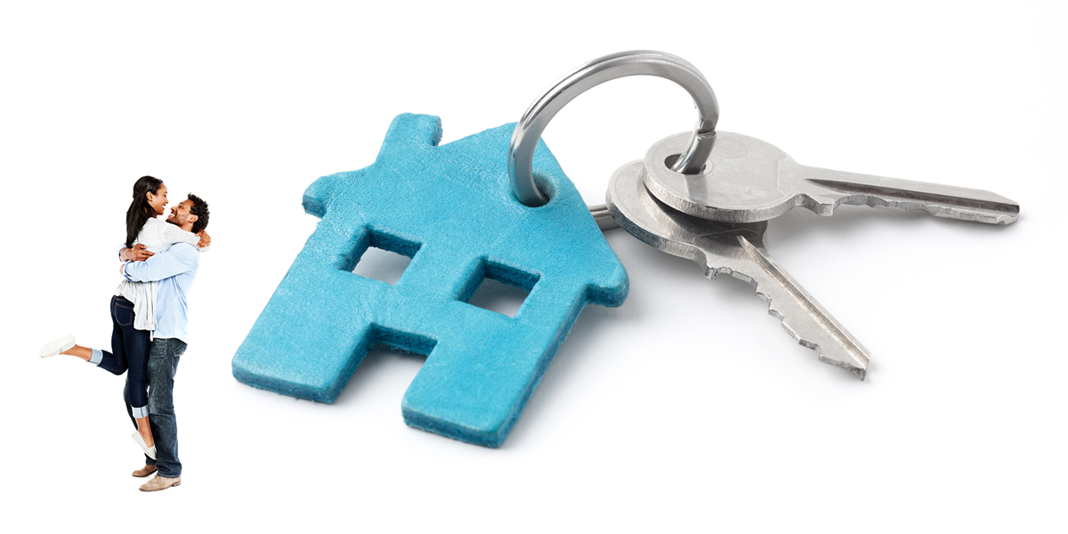 Happy couple hugging beside large set of house keys