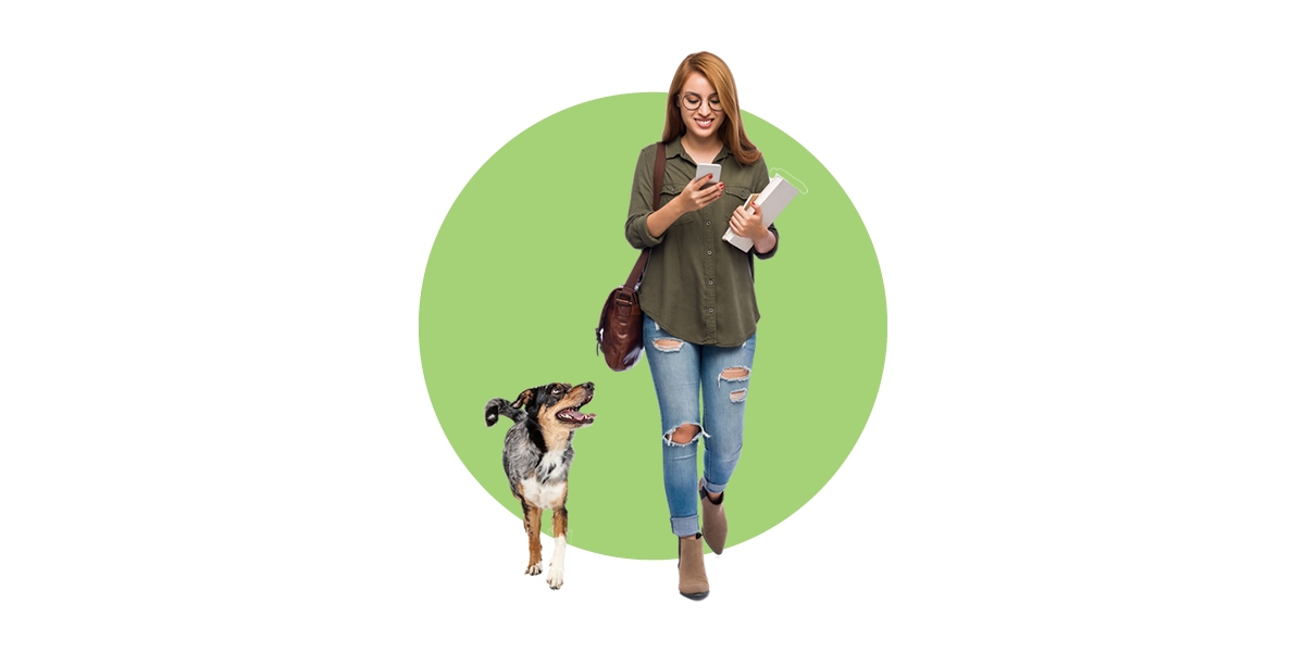 A female student on her phone walking with her dog