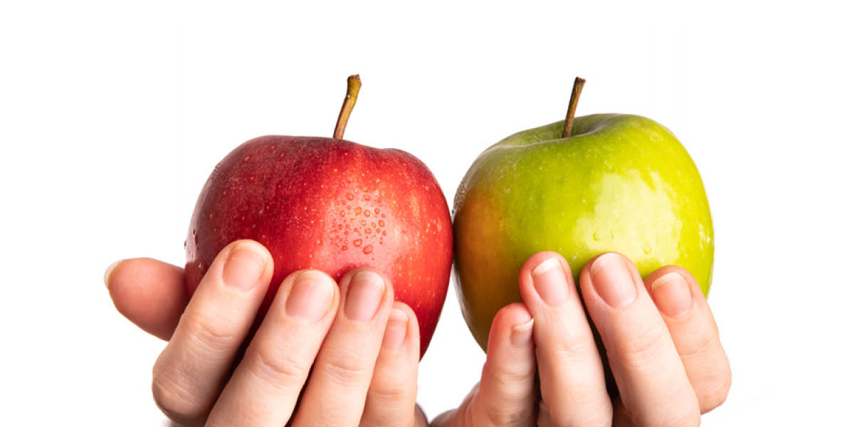 Hands holding a red apple and a green appl.